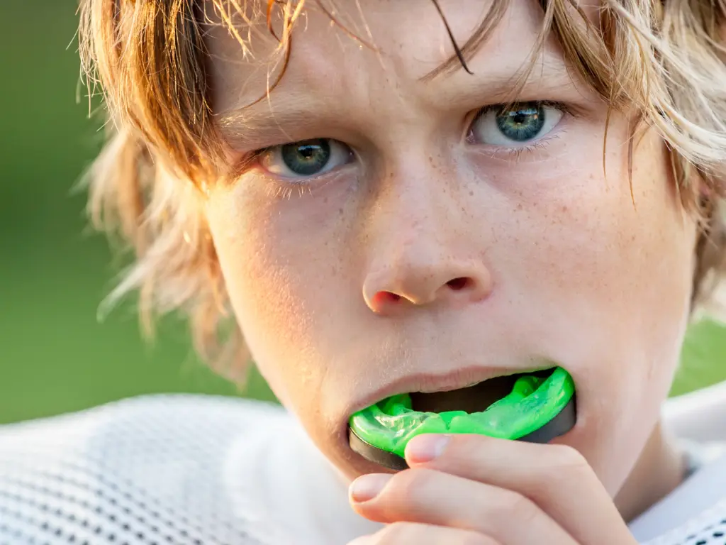 Child athlete putting in a mouth guard for sports