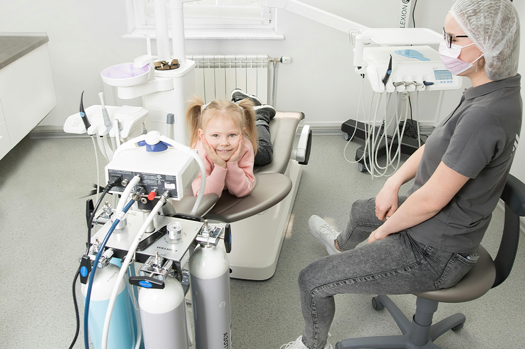Smiling child in a dental chair with a pediatric dentist during emergency dental care in Houston